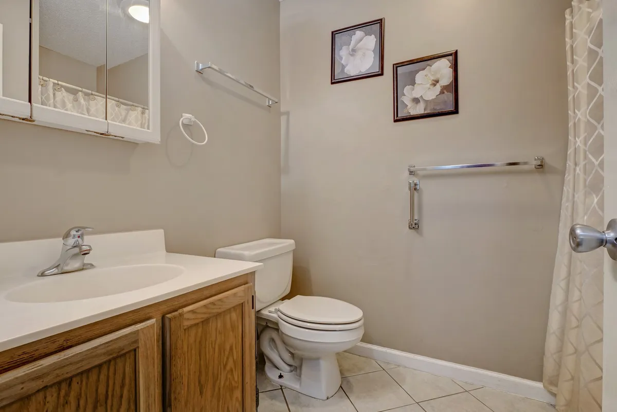 A clean, tranquil bathroom with a modern sink, toilet, and decorative art on the walls. Soft light and a subtle shower curtain contribute to a spa-like ambiance, making it a welcoming space for guests of all ages.