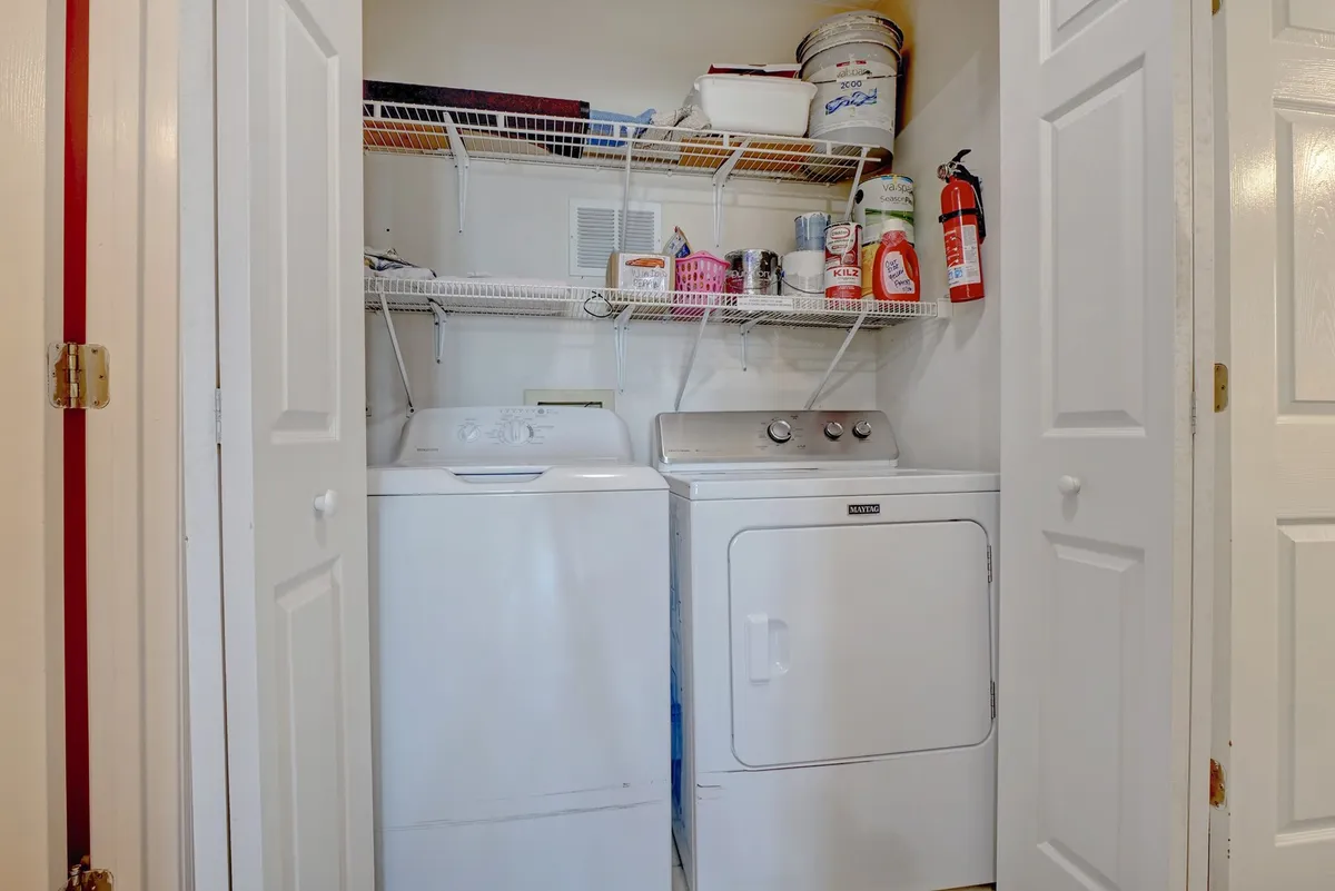 A dedicated laundry area with a modern washer, dryer, and organized shelving stocked with laundry supplies. The space is clean, bright, and practical, emphasizing ease and convenience for families after a beach day.